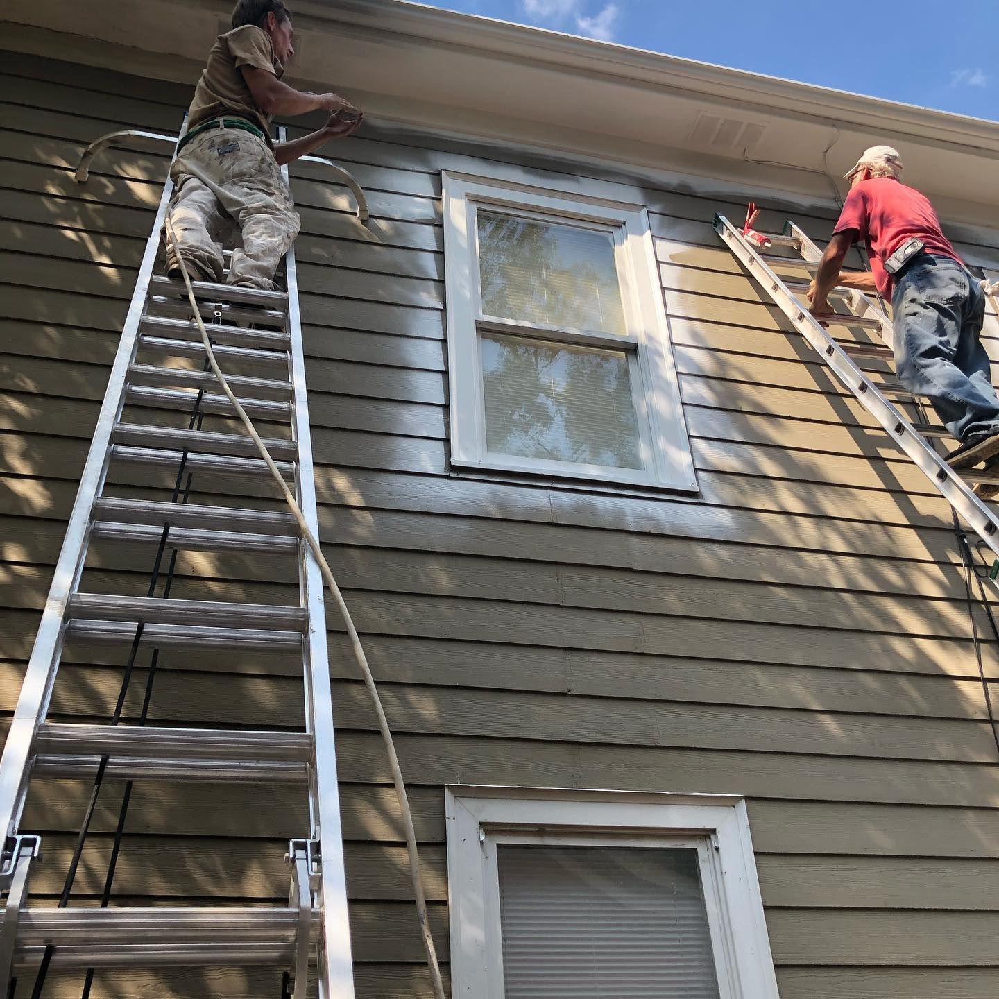 Two men are painting the side of a house.