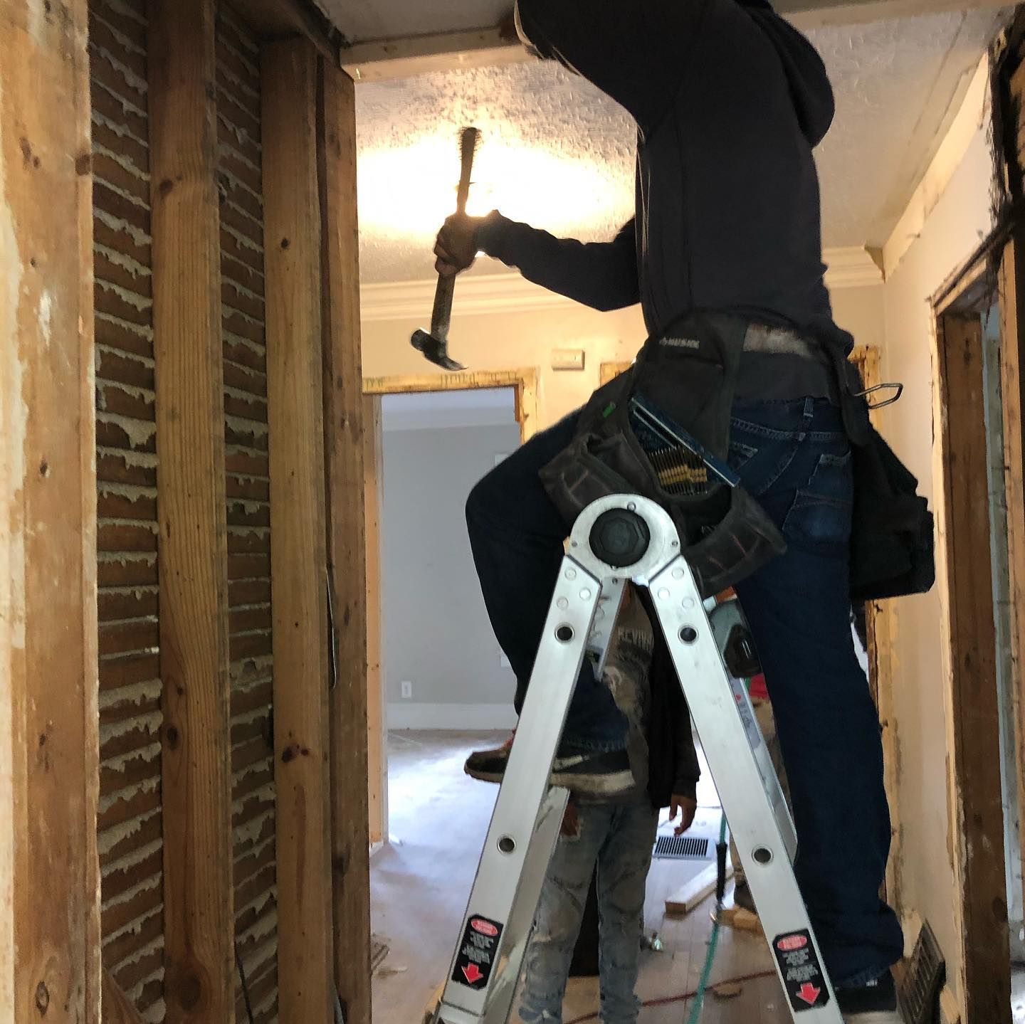 A man standing on a ladder holding a hammer