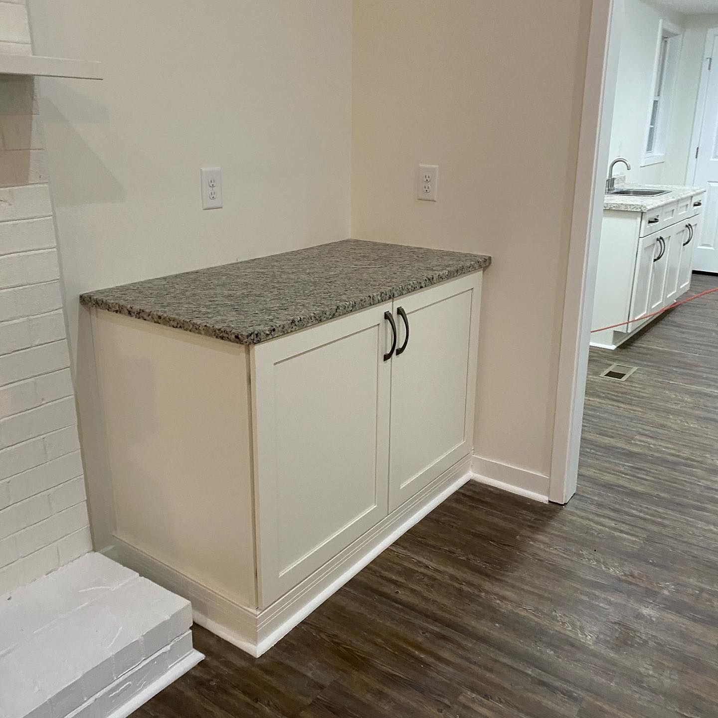 A white cabinet with a granite counter top in a kitchen.