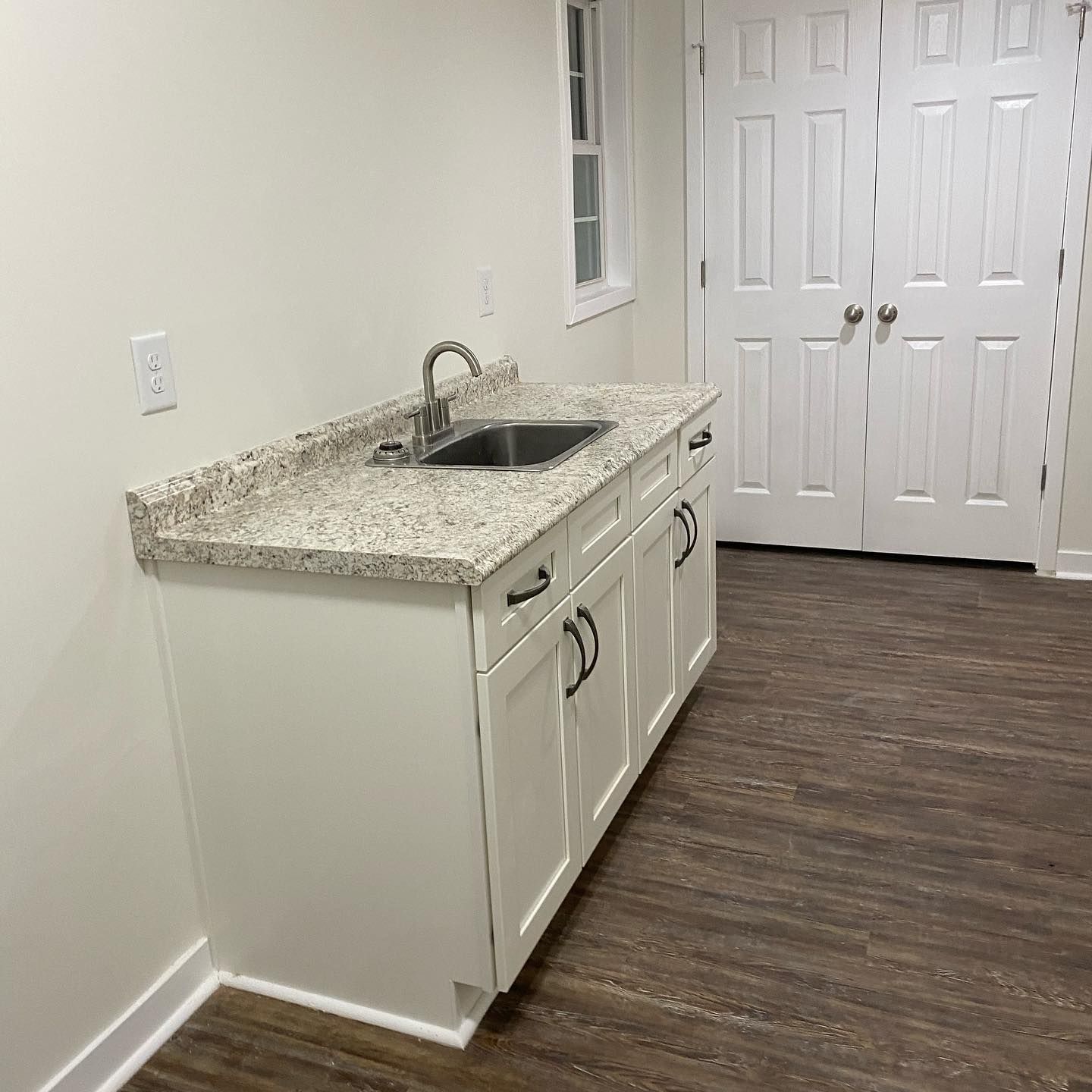 A kitchen with white cabinets , granite counter tops , and a sink.