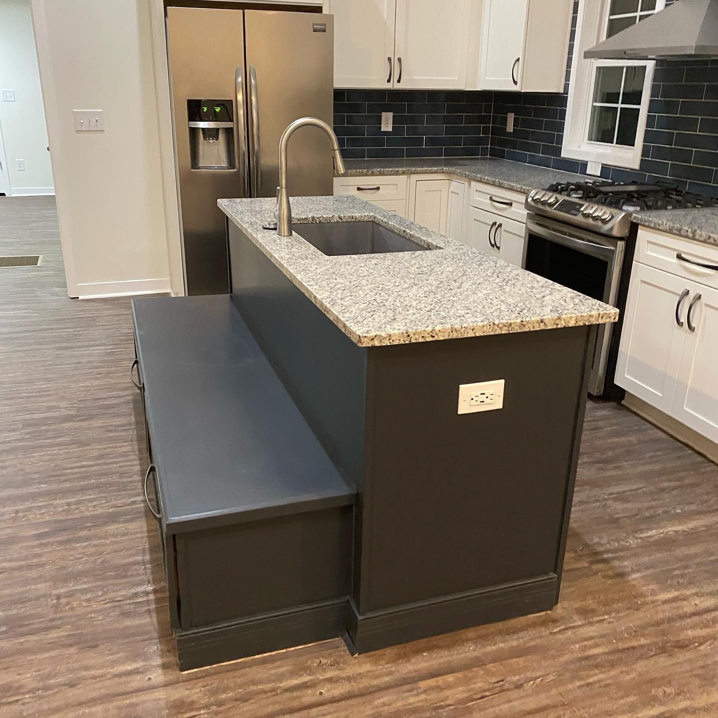 A kitchen with a large island with a sink and a bench.