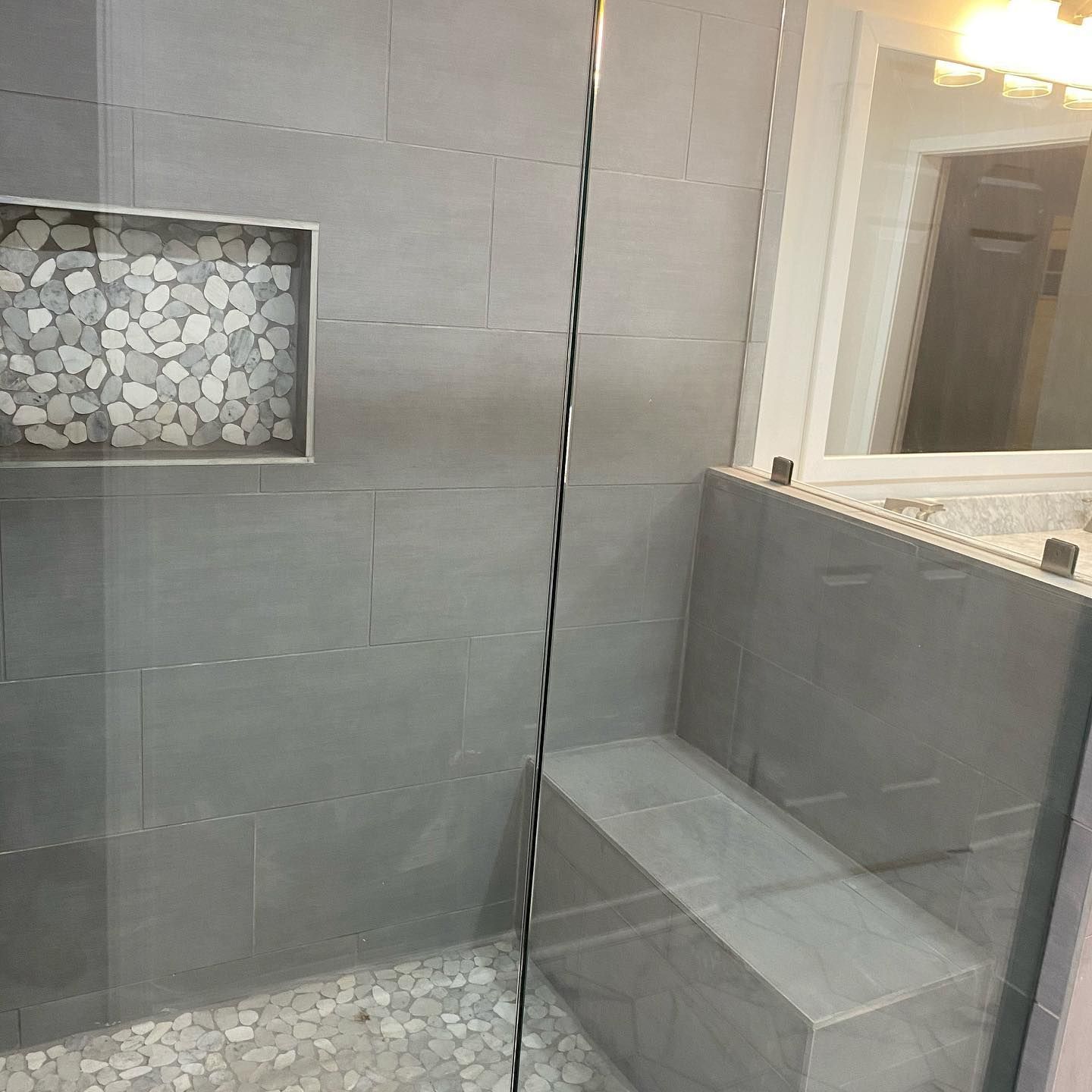 A bathroom with a walk in shower and a bench