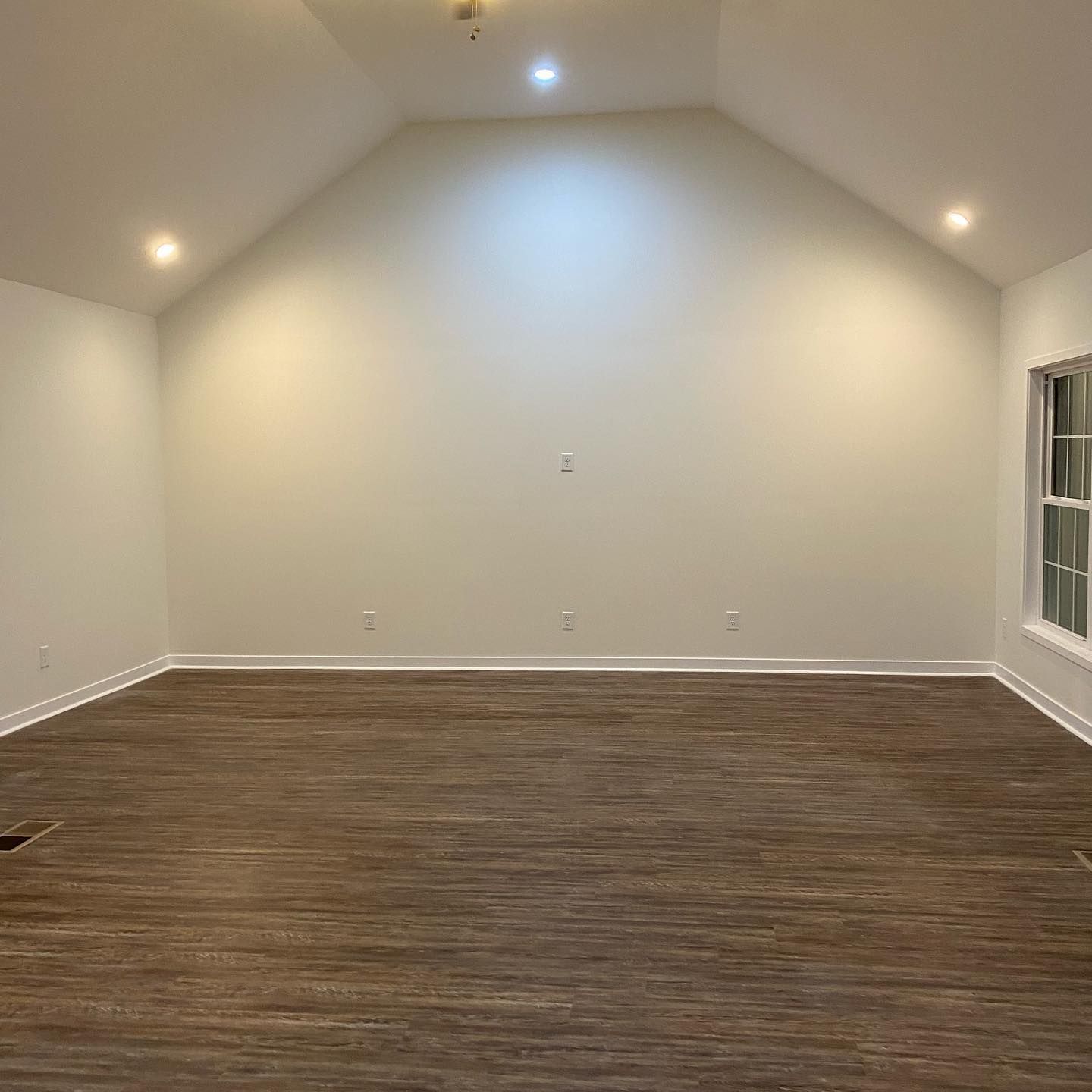 A large empty room with a vaulted ceiling and a wooden floor.