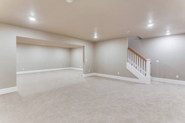 An empty basement with a staircase leading up to the second floor.