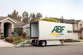 Moving truck with ramp parked in a suburban driveway near a house