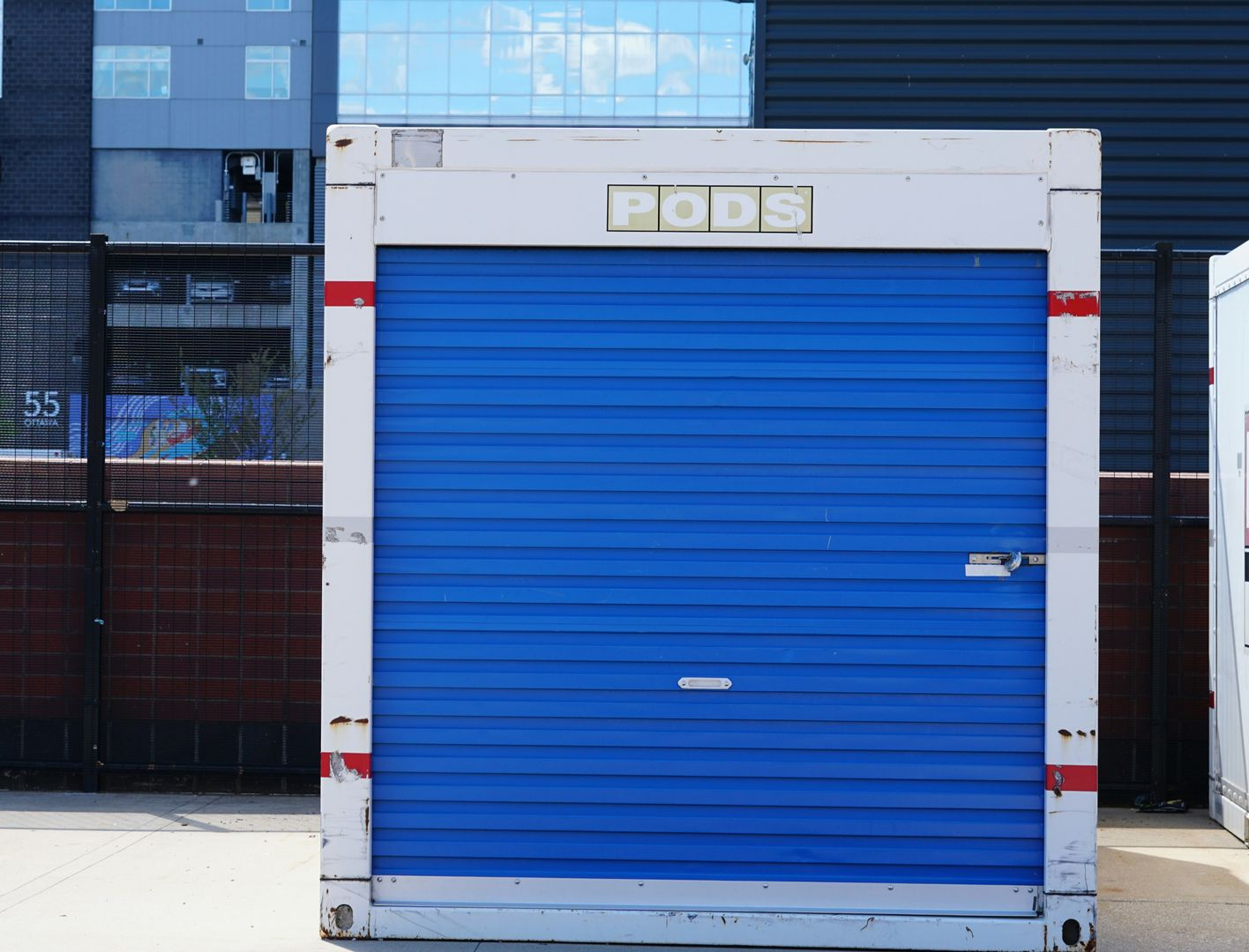 Blue metal storage unit with white trim in front of a building
