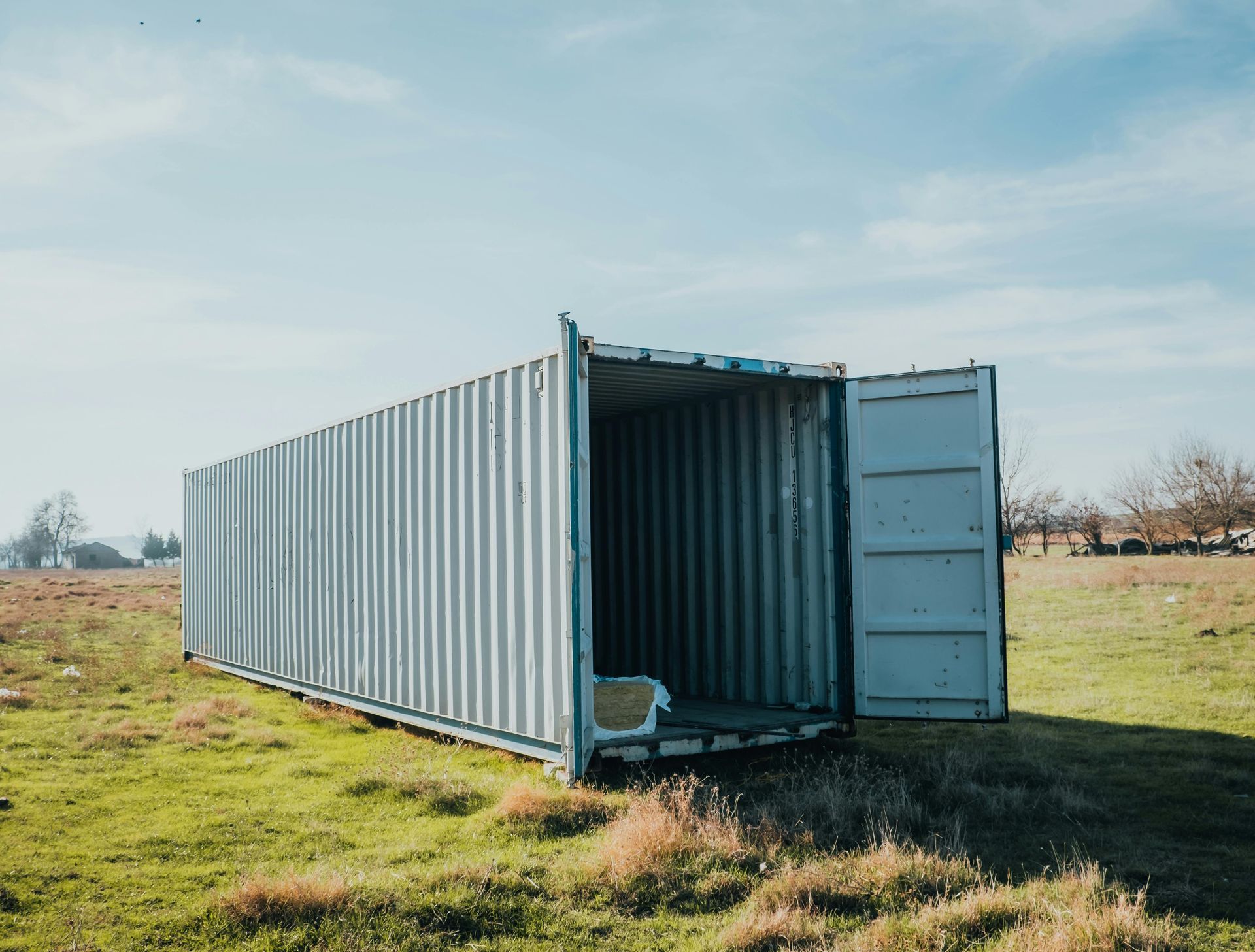 Open shipping container in a grassy field under a pale sky