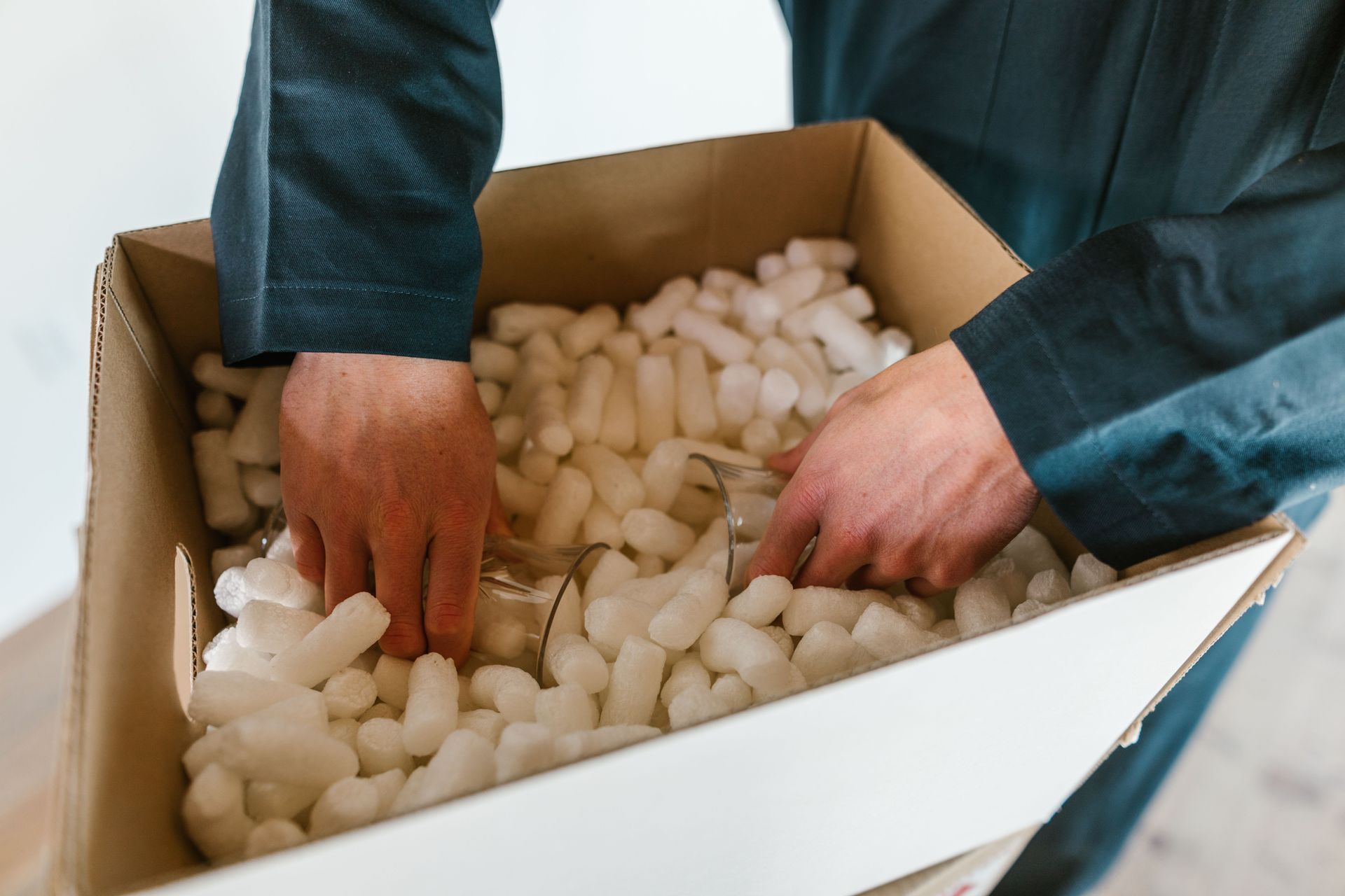 Hands sorting white packing peanuts in an open cardboard box
