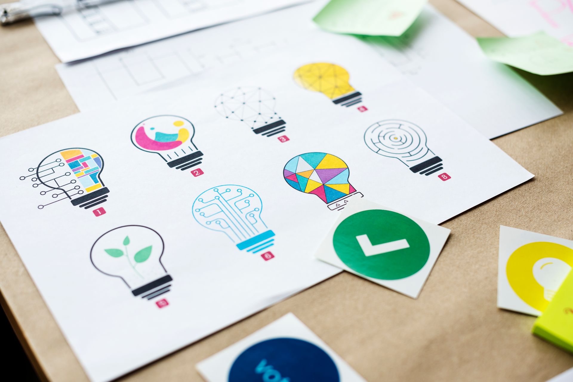 Hojas con coloridos iconos de bombillas y relojes sobre un escritorio, que muestran un concepto de lluvia de ideas.
