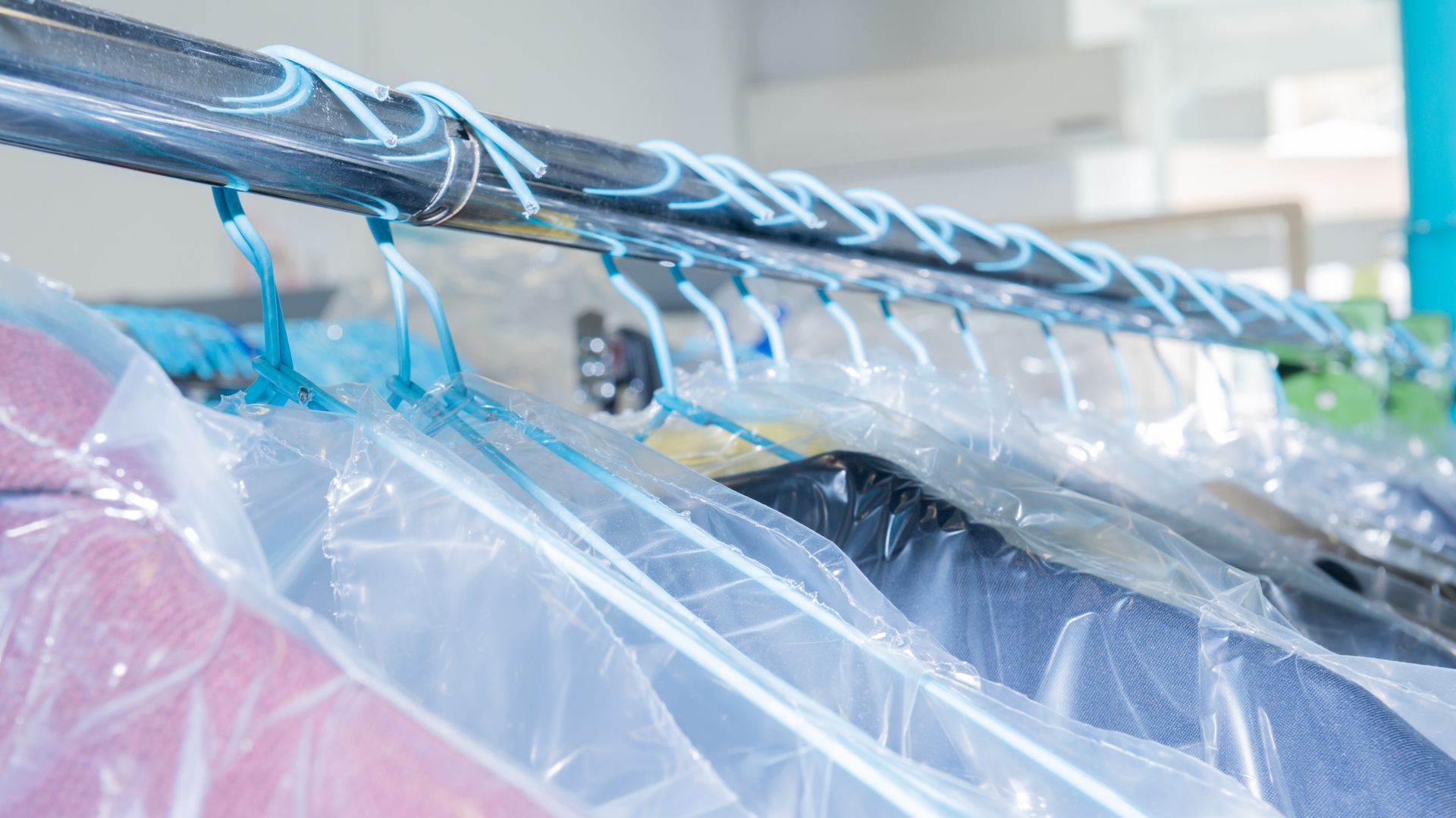 Un mucchio di vestiti appesi su uno scaffale in sacchetti di plastica.