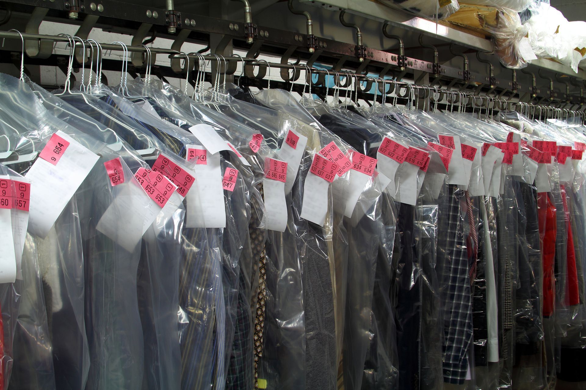 Una fila di vestiti appesi in sacchetti di plastica con etichette rosa
