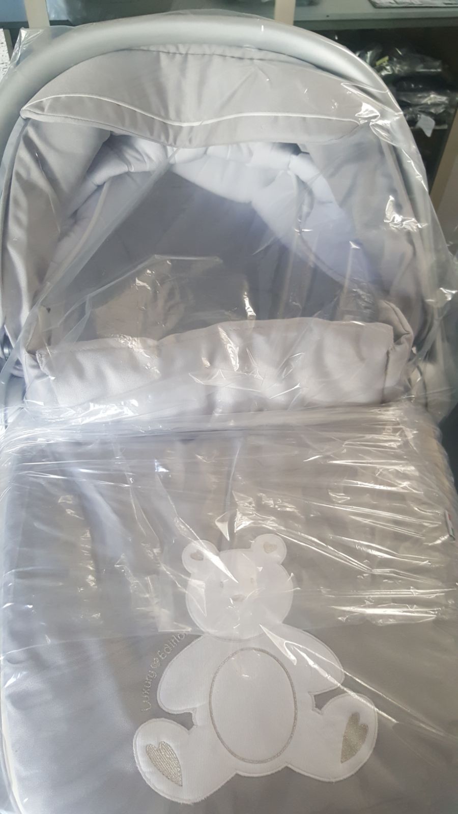 Un passeggino è avvolto nella plastica e ha un orsacchiotto sopra.