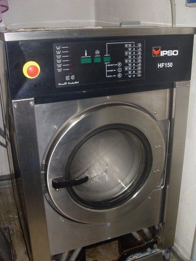 Una lavatrice in acciaio inossidabile è appoggiata sul pavimento di una stanza.