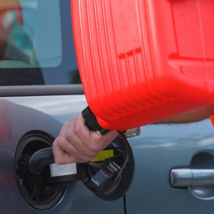 A person is pouring gas into a car