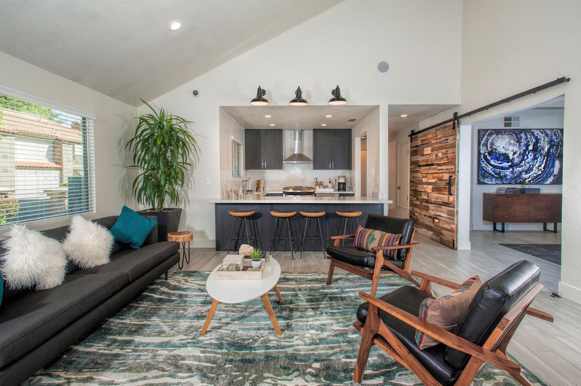 Open-concept living area with a kitchen island, bar stools, and modern furnishings.