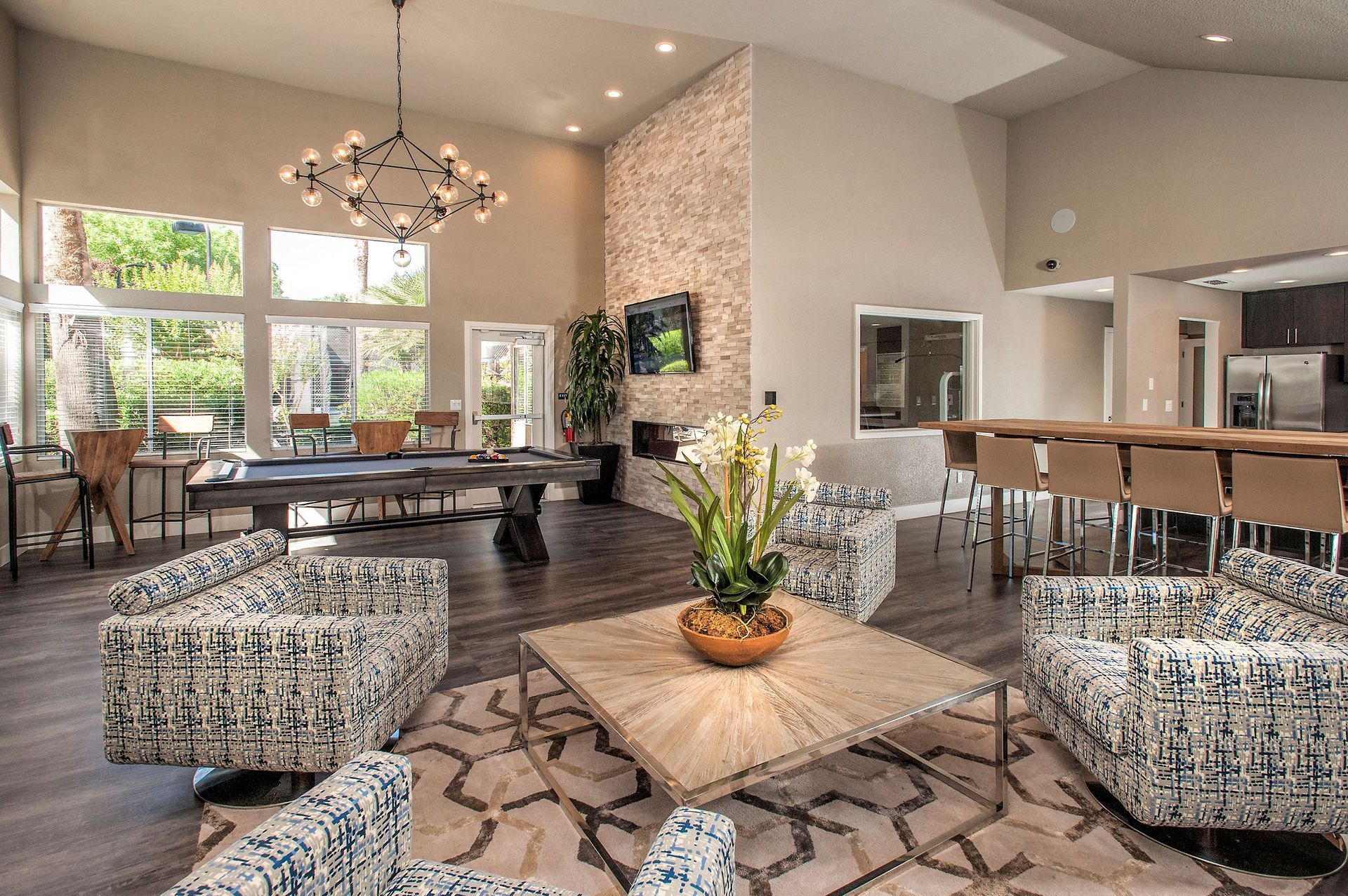 Interior community lounge with seating, a billiards table, and a kitchenette area.