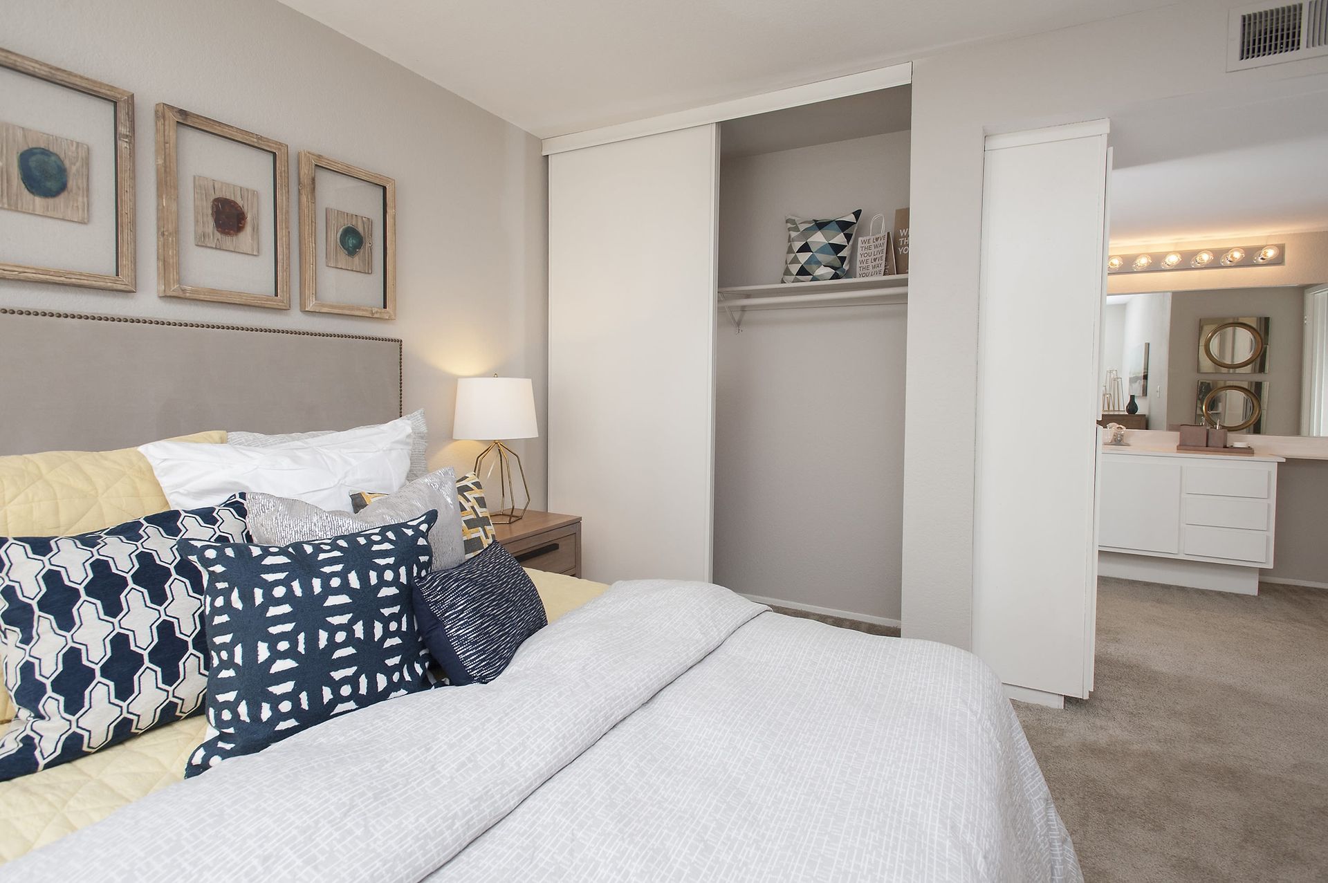 Bedroom in a modern apartment with a bed, pillows, nightstand, and open closet.