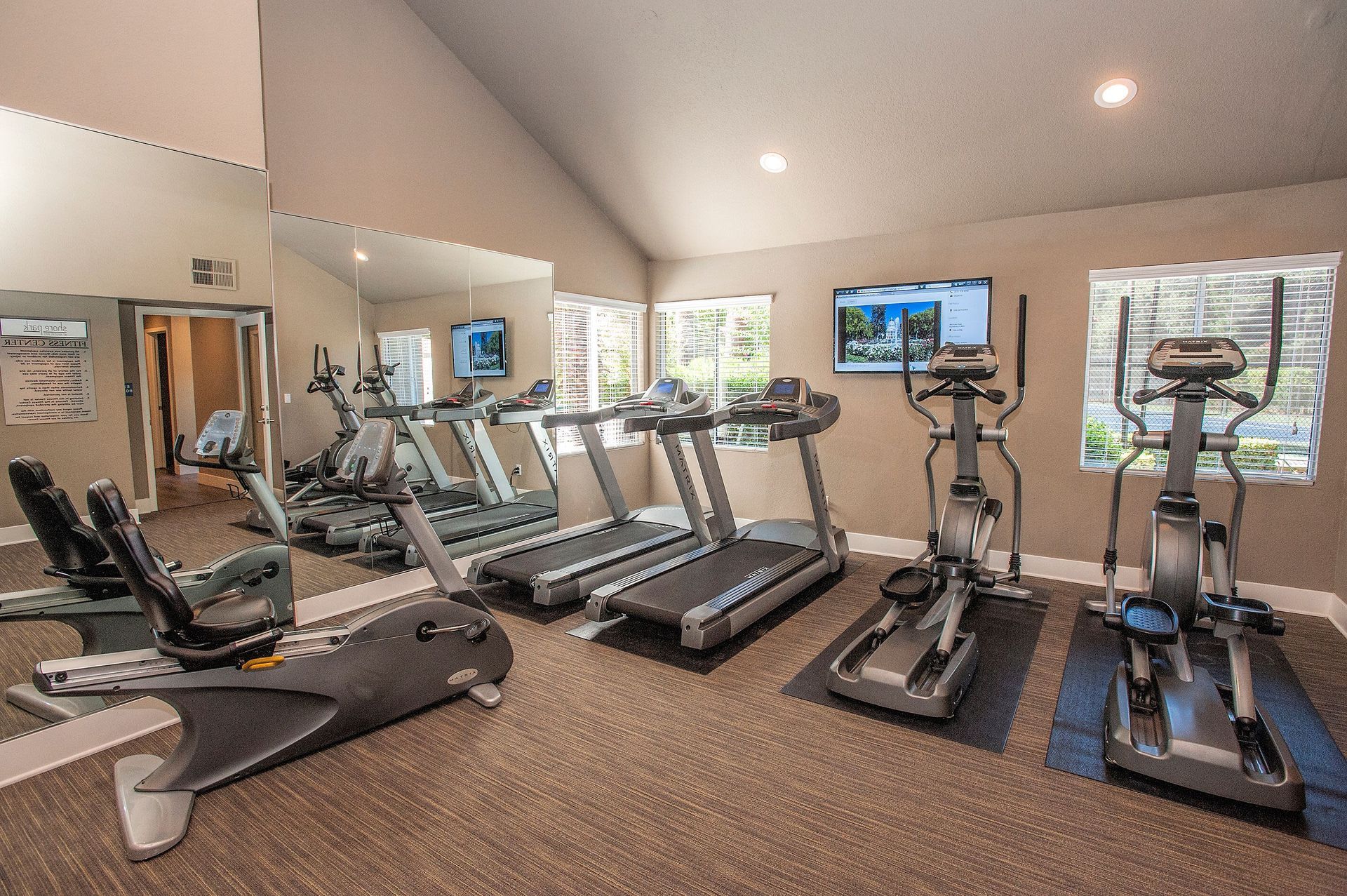 Indoor fitness center with treadmills, ellipticals, a stationary bike, and a mirrored wall.
