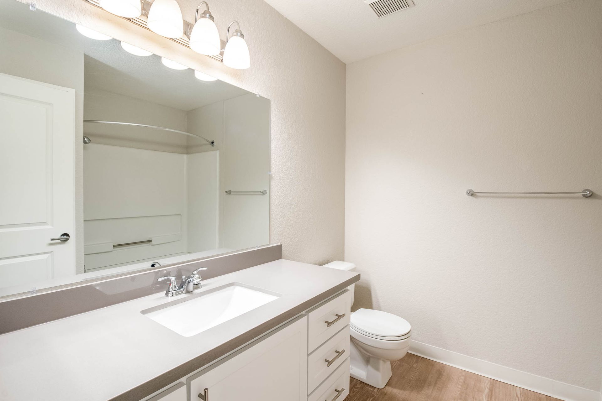 Bathroom vanity with sink, mirror, and toilet in an apartment.