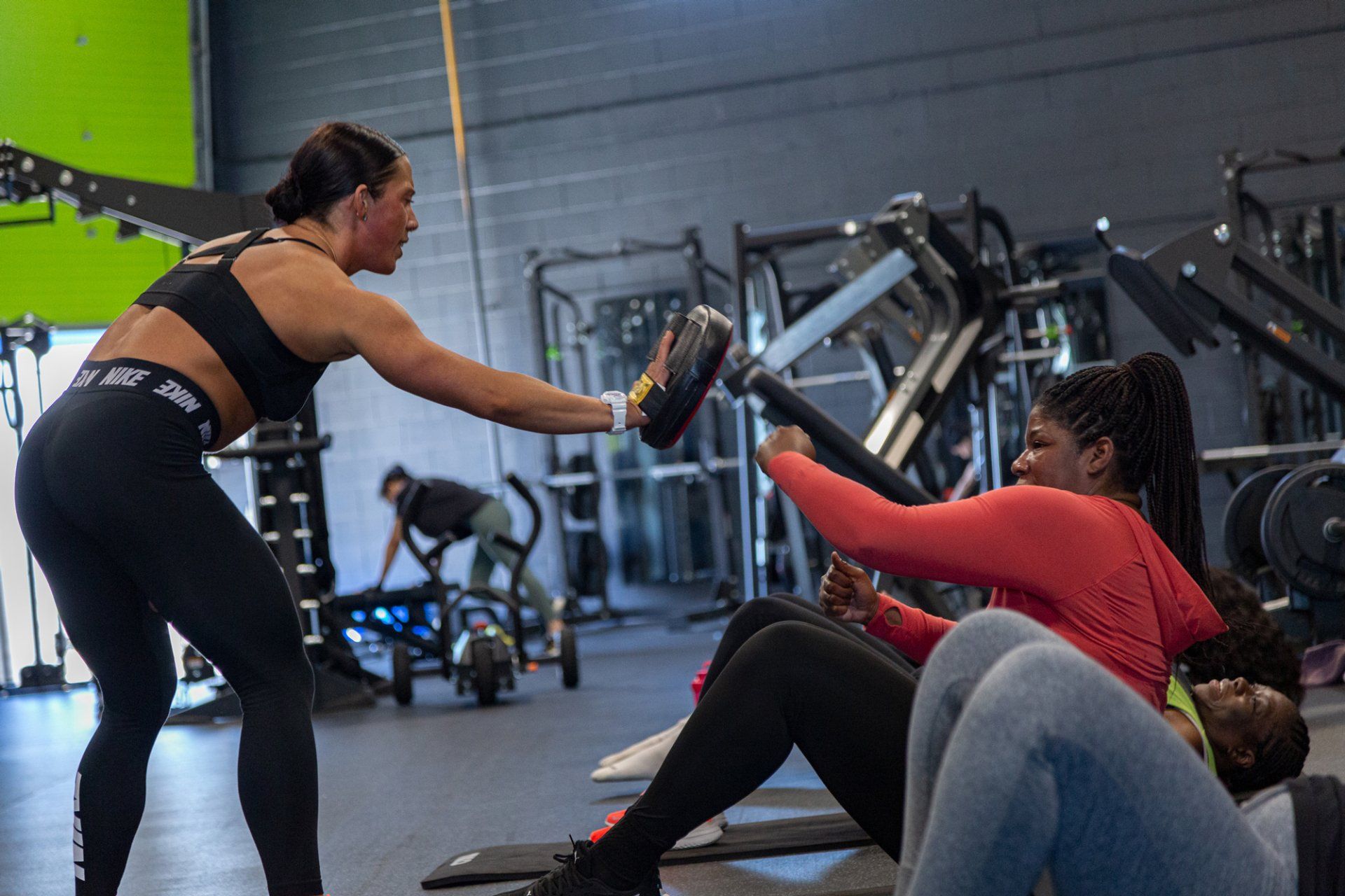 a woman is teaching two women how to do exercises in a gym .