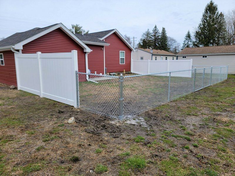There is a chain link fence in the backyard of a house.