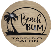 A round, wood-grain sign with a black palm tree silhouette and the text "Beach BUM TANNING SALON."