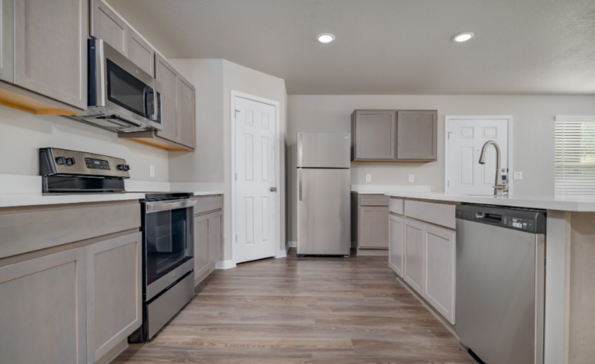 Gray kitchen with stainless steel appliances, light cabinets, and wood-look flooring.