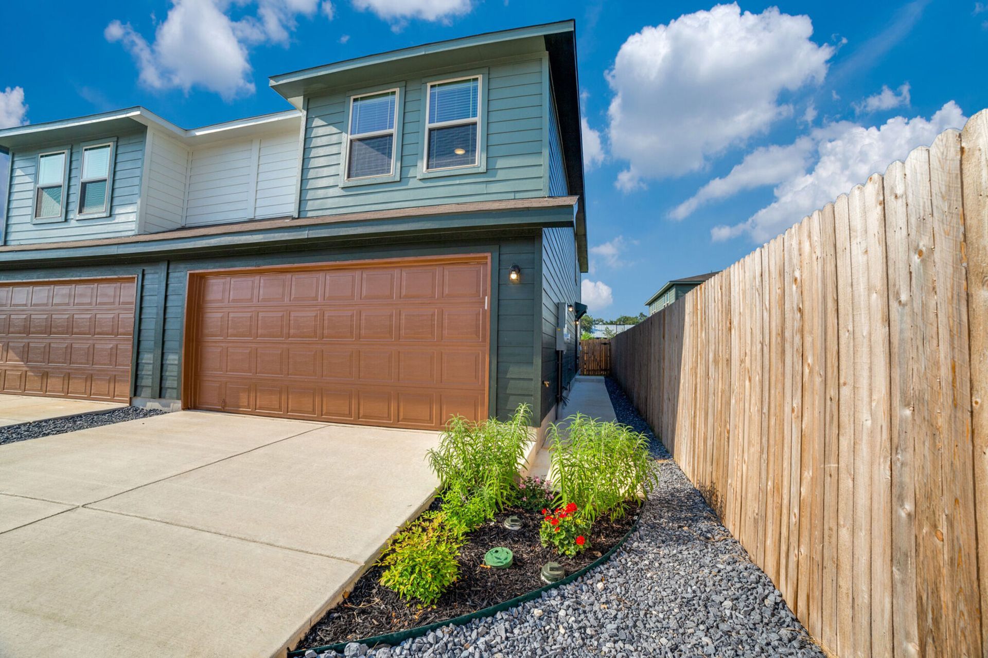 Townhouse exterior with blue siding, brown garage door, and wooden fence.