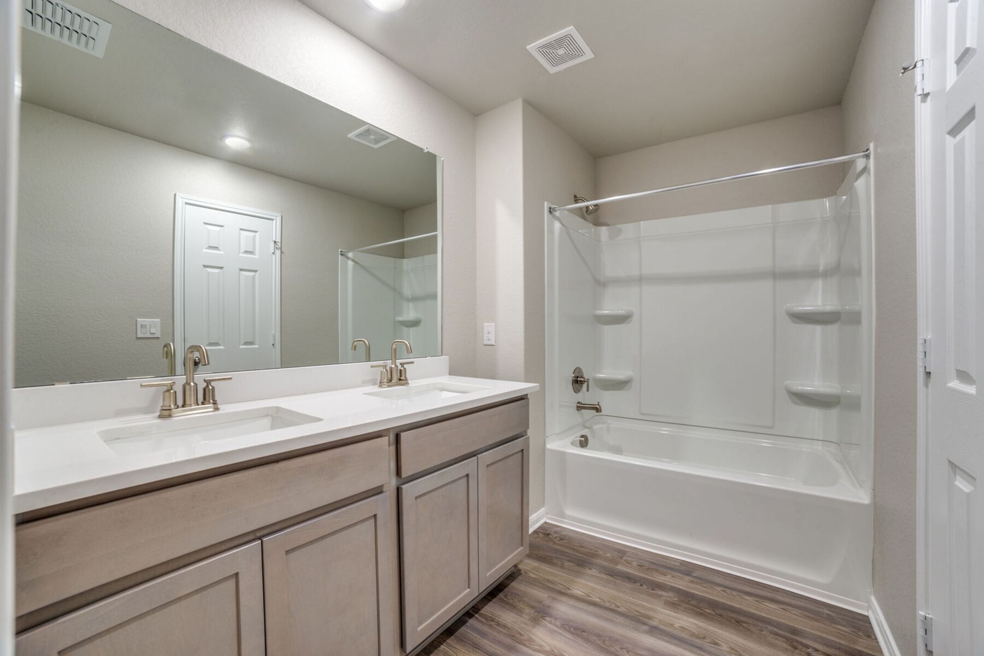Bathroom with double vanity, bathtub/shower, and neutral color scheme.