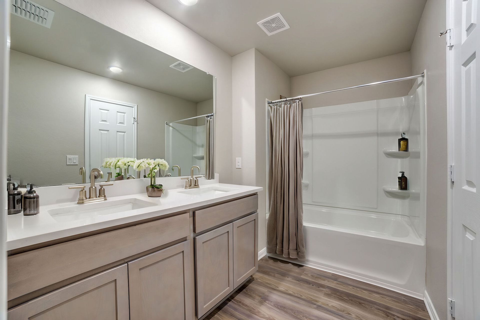 Bathroom with double vanity, bathtub/shower, and neutral color scheme.