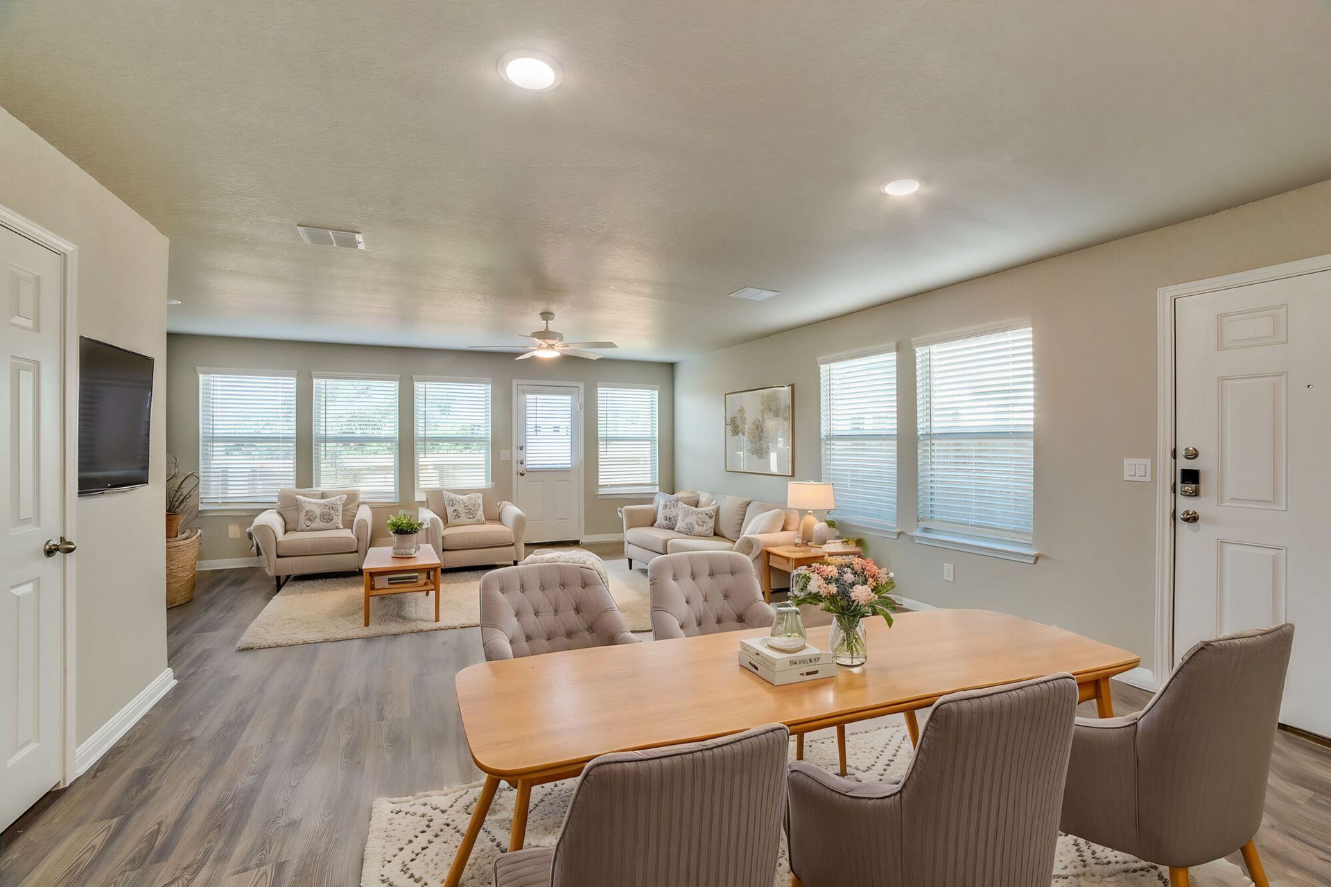 Spacious living and dining area with gray walls, gray flooring, and light-colored furniture.