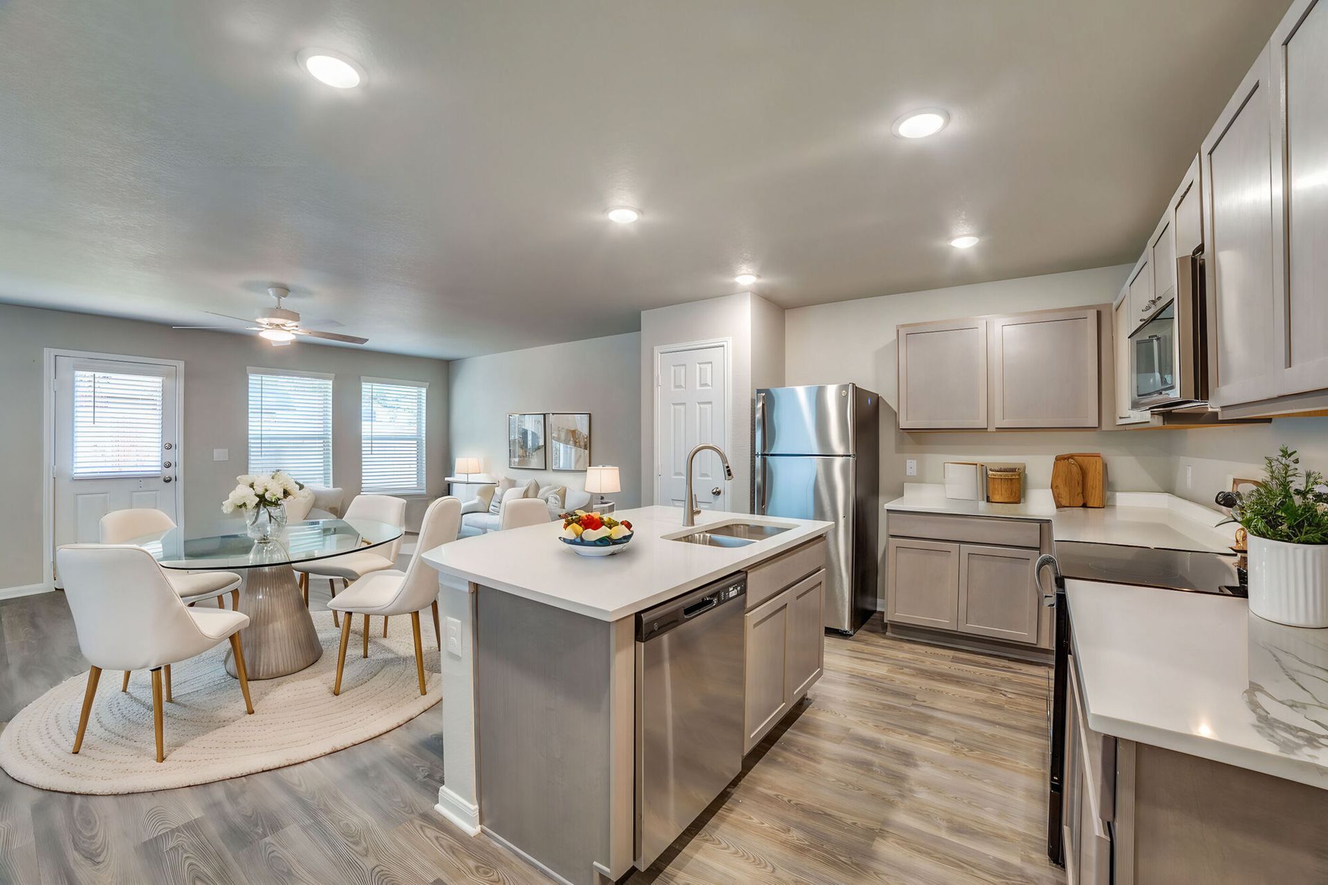 Open-concept kitchen and dining area with gray cabinets, stainless appliances, and a round table.