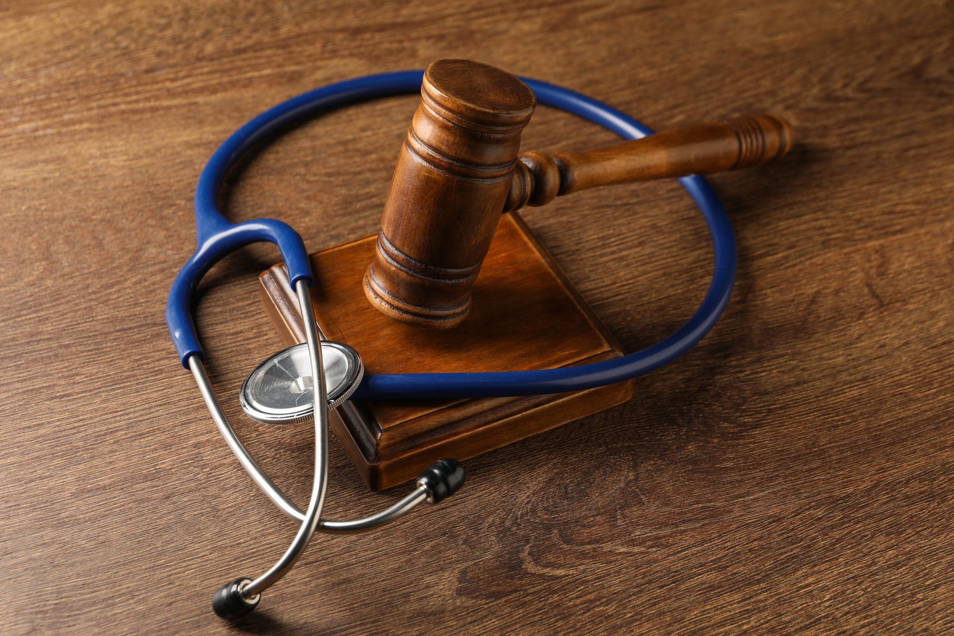 A wooden gavel and stethoscope are on a wooden table.