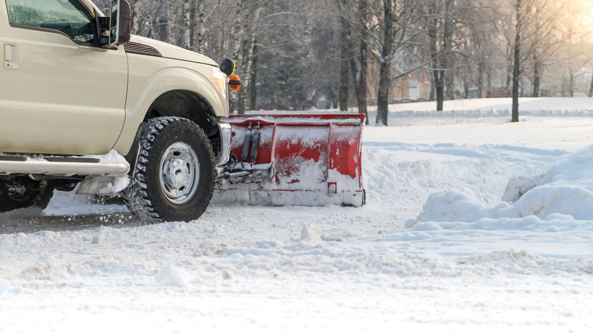 Un camion déneige une route enneigée.
