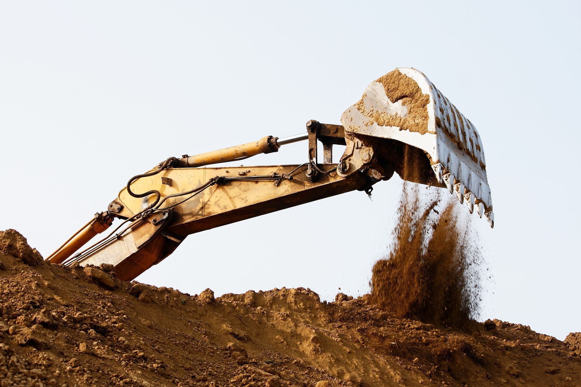 Un bulldozer ramasse de la terre sur une colline.