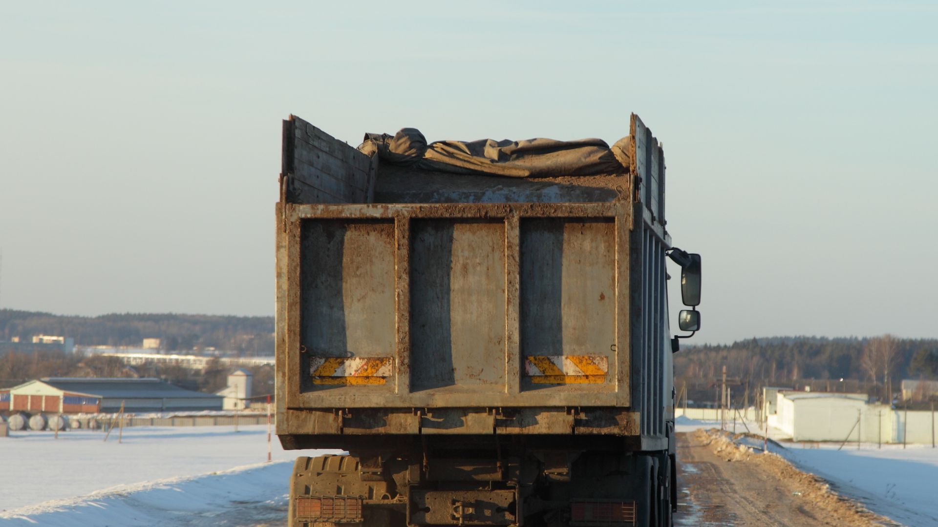 Un camion à benne basculante charge du sable dans un tas.