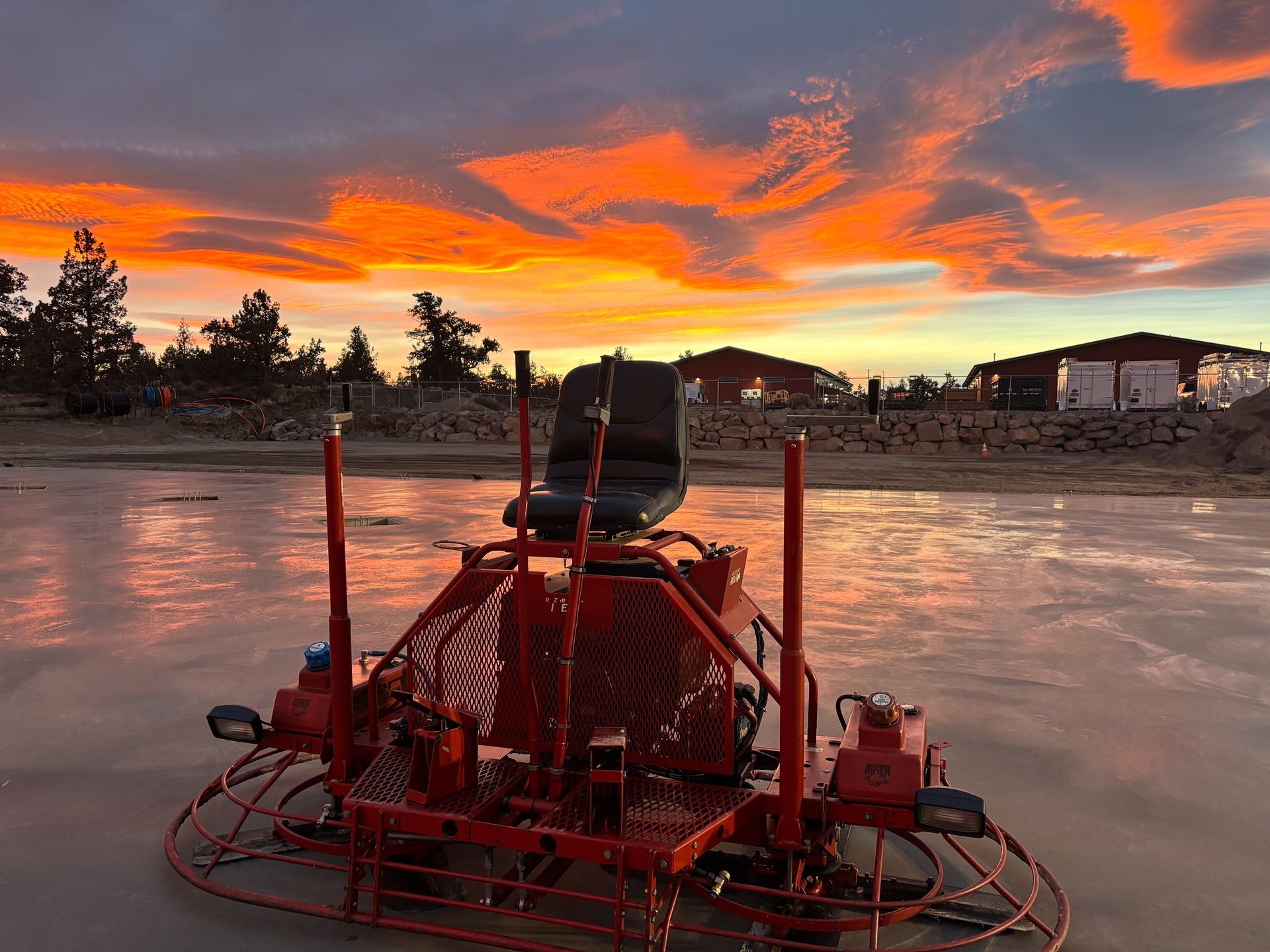 Concrete finishing machine on a flat surface, with a colorful sunset in the background.
