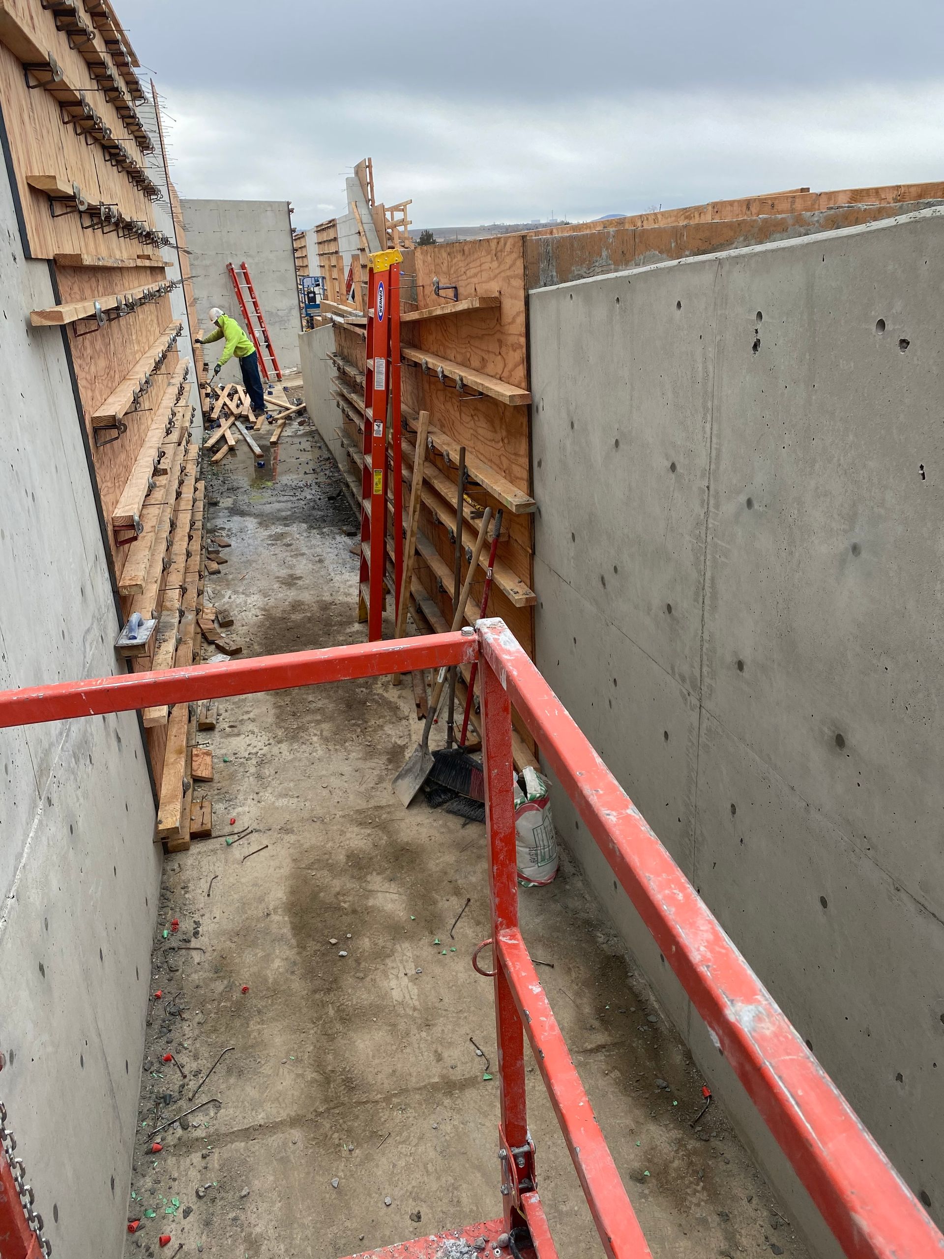 Construction site with workers, concrete walls, wooden framework, and scaffolding.