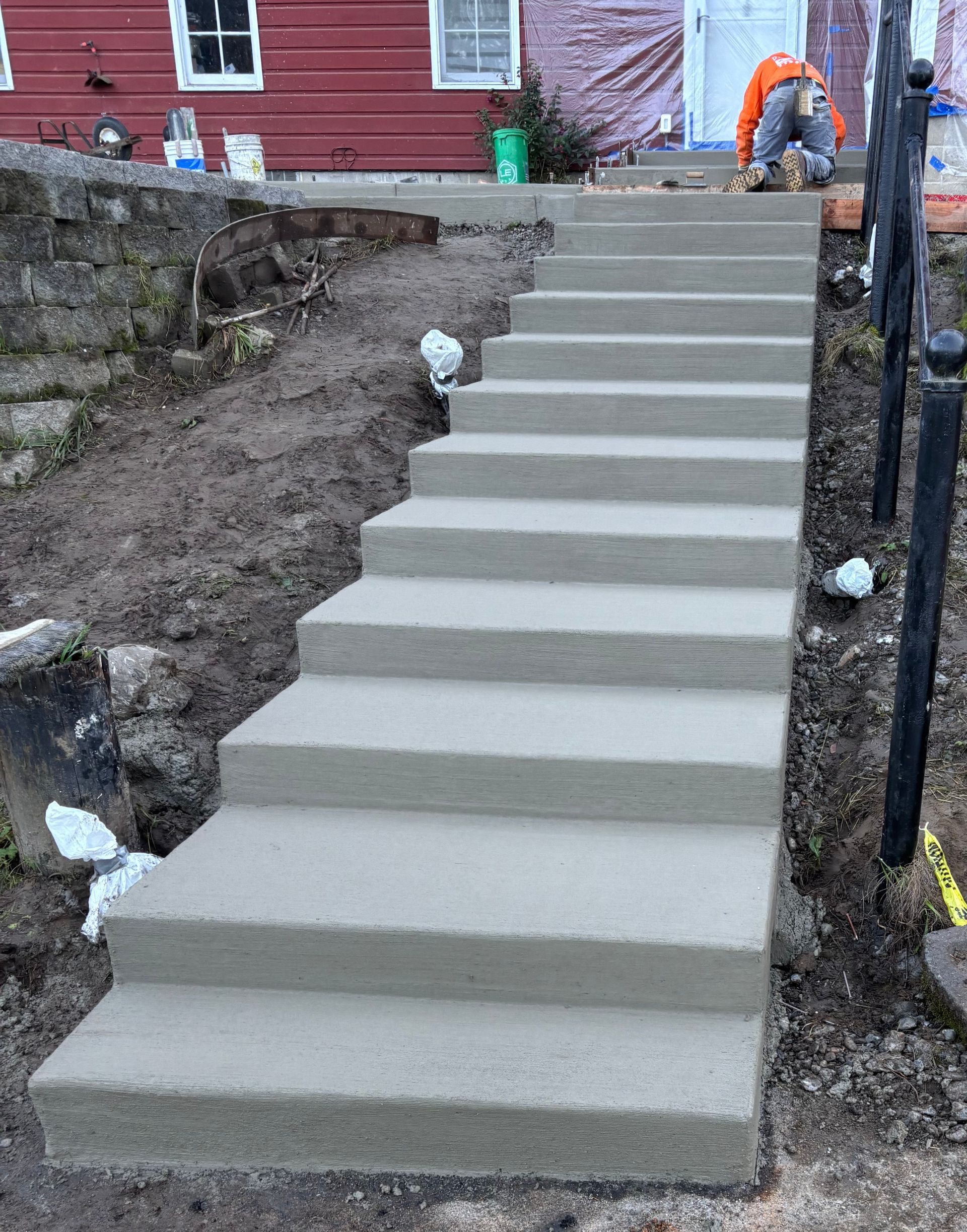Concrete steps leading up to a red building; a construction worker works near the top.