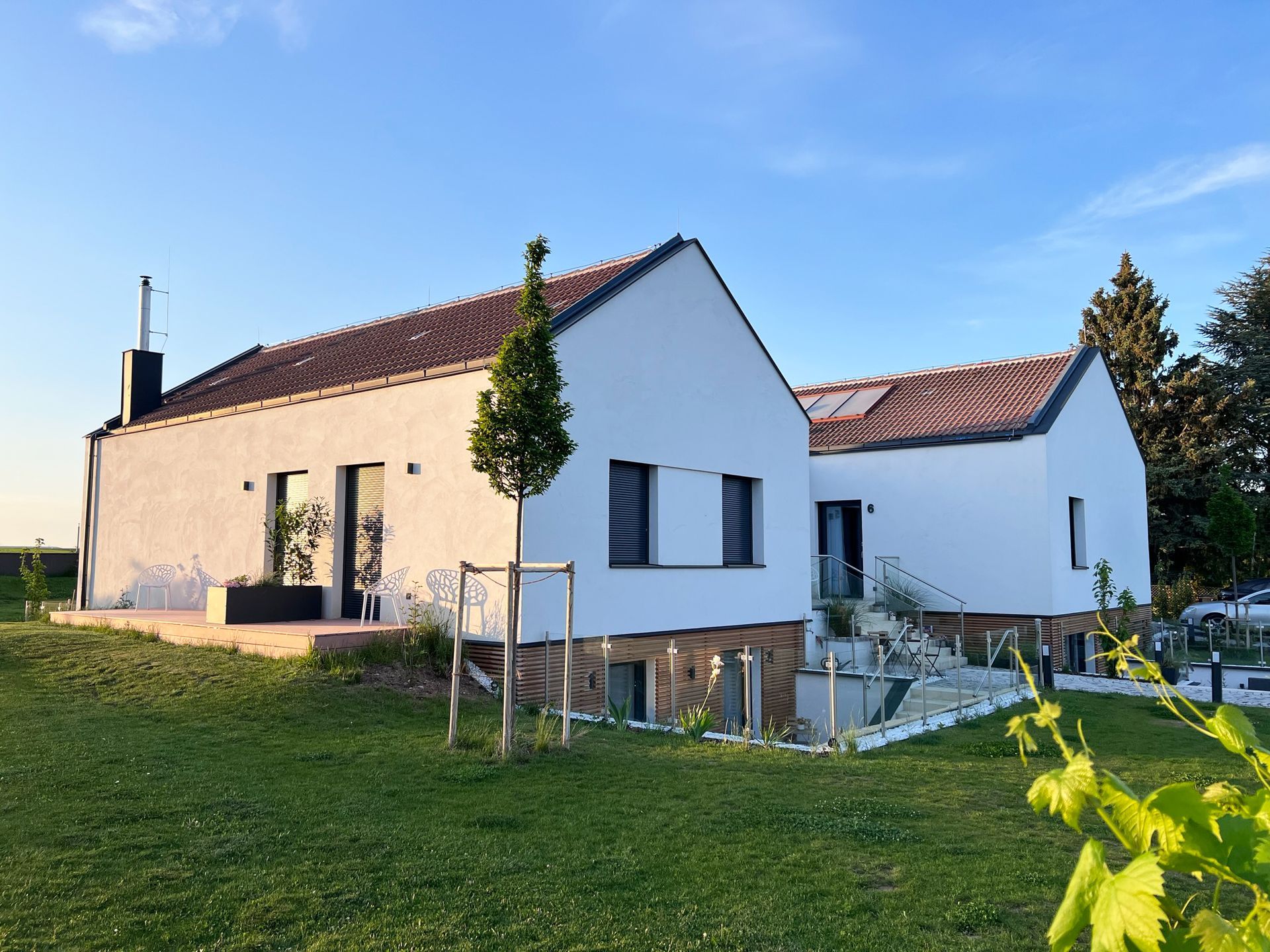 Außenansicht von geislerAppartments. Weißes großes Haus mit Holzelementen. Es ist umgeben von grünem Rasen.