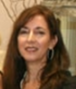 Woman with long brown hair wearing hoop earrings smiles.