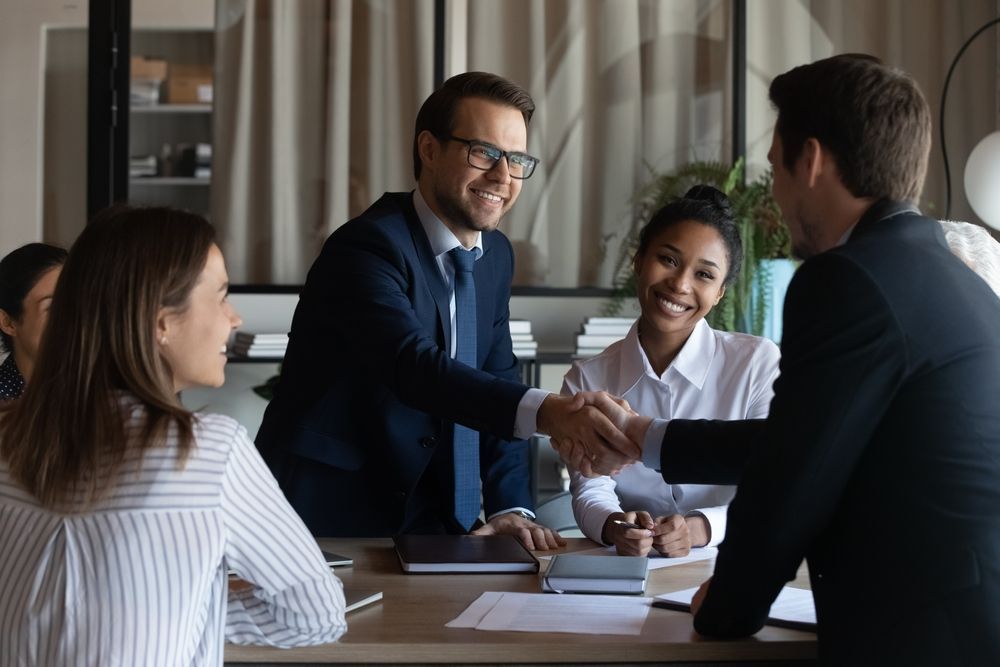 A group of business people are shaking hands at a table.
