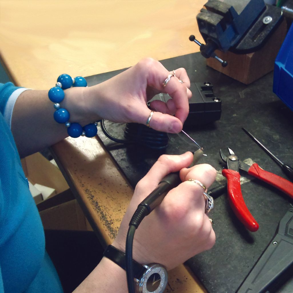 A woman wearing a bracelet is working on a piece of equipment