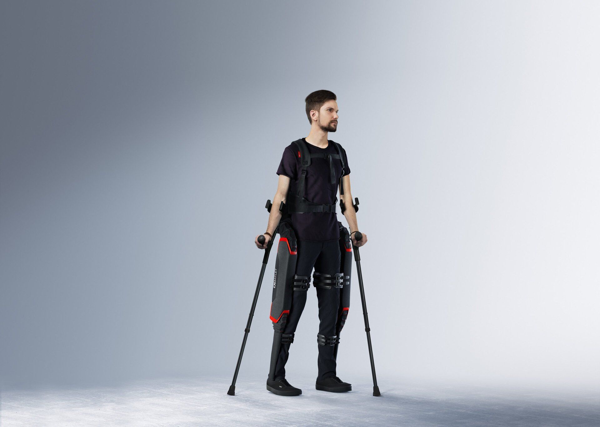A man in an exoskeleton is standing with crutches.