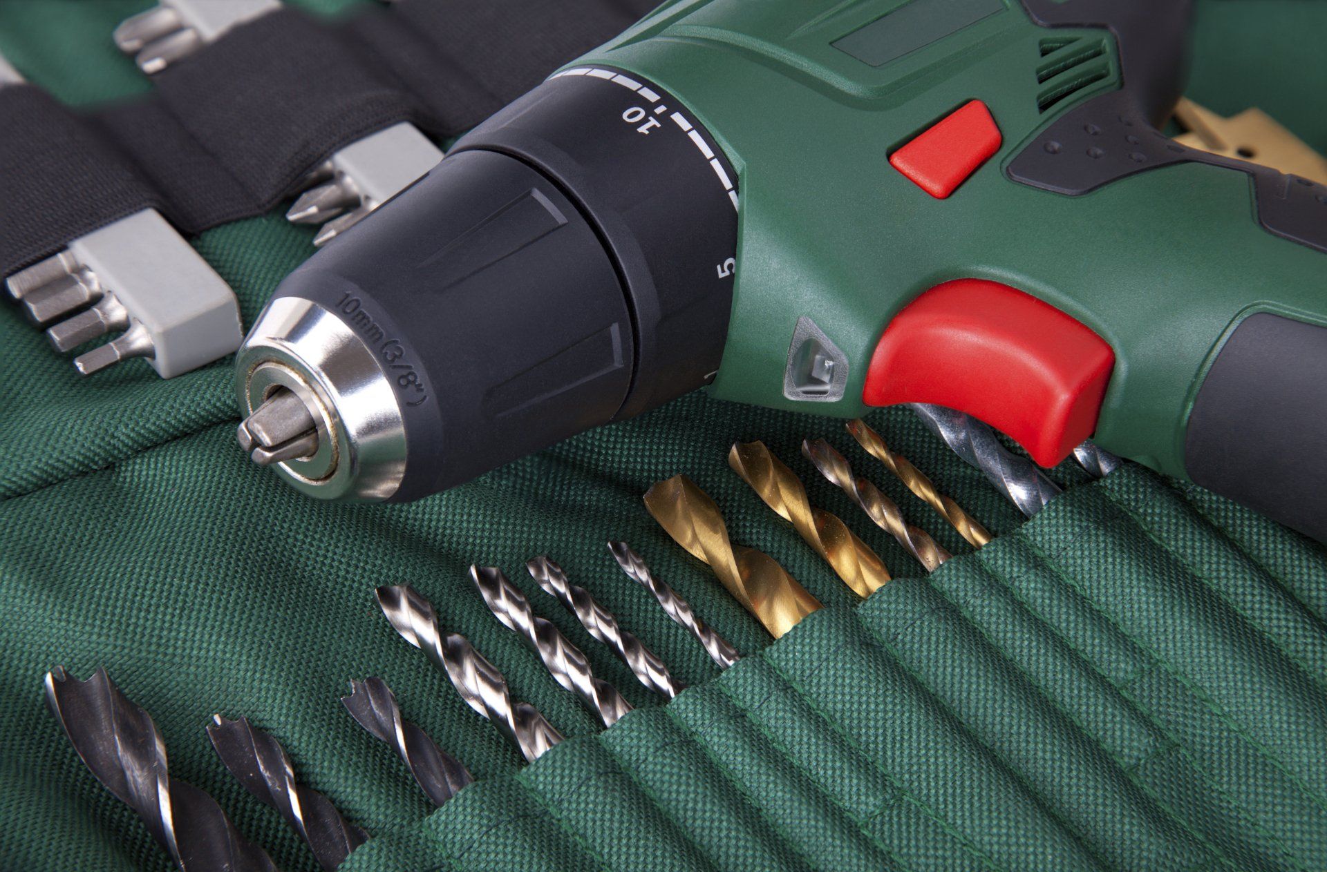 A drill is sitting on top of a bag of drill bits.