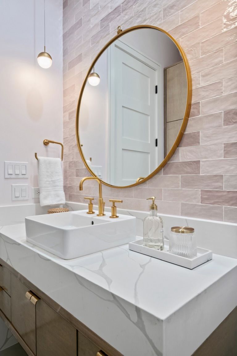 A bathroom with a sink and a round mirror.