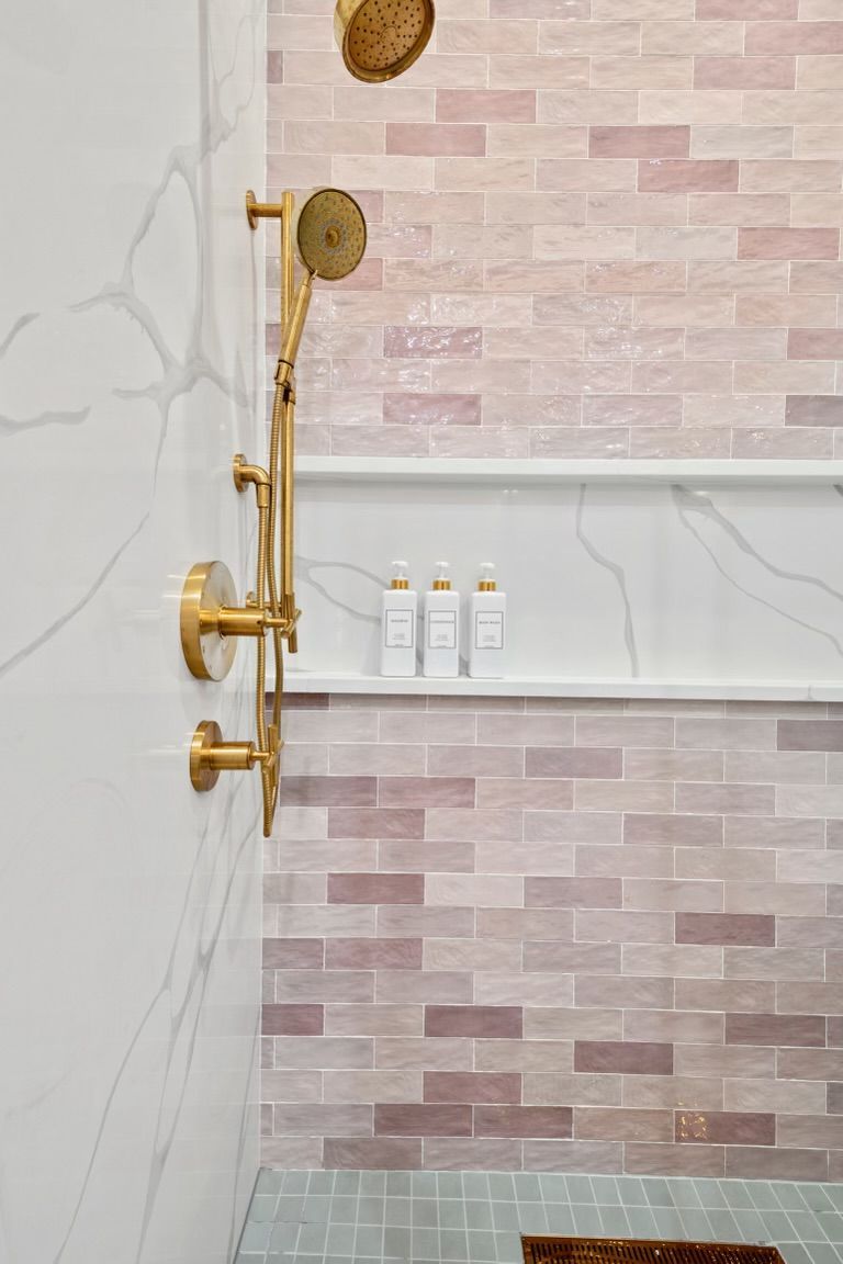 A shower with a brick wall and a shelf with shampoo bottles on it.
