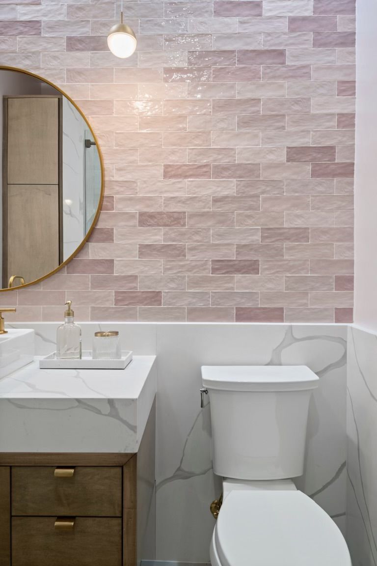 A bathroom with a toilet , sink and mirror.