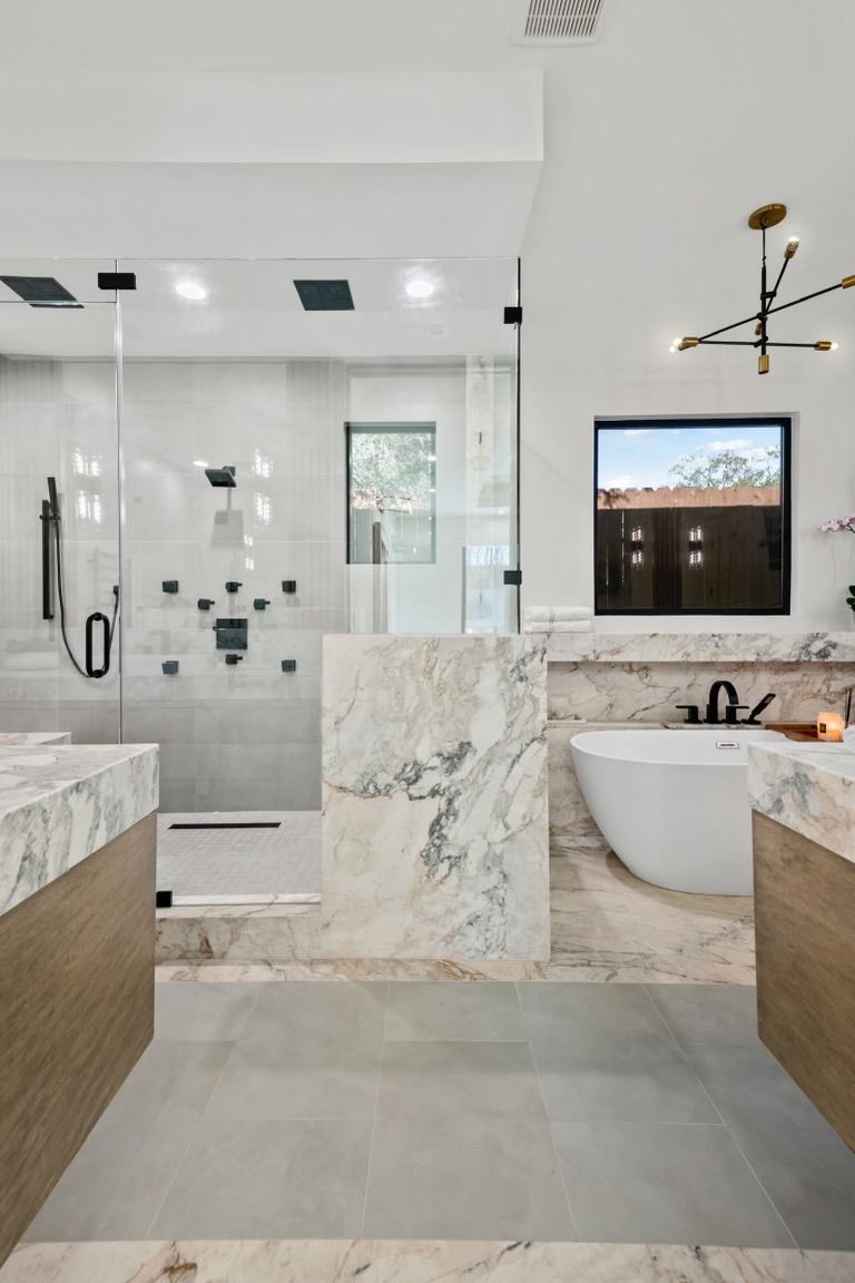 A bathroom with a tub , sink , shower and window.
