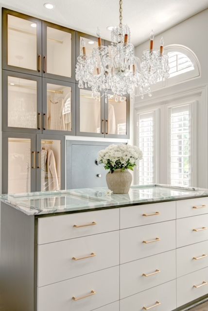 A walk in closet with lots of drawers and a chandelier.